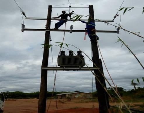 Muchinda technicians constructing an overhead power line and transformer platform in a rural setting