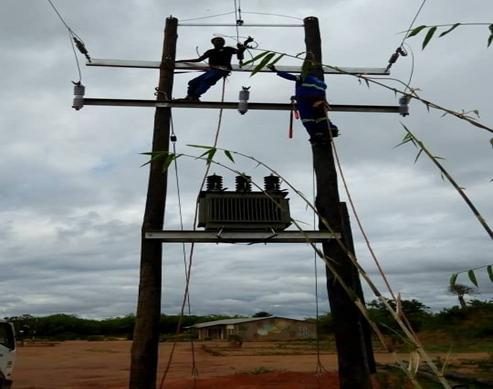 Muchinda technicians constructing an overhead power line and transformer platform in a rural setting